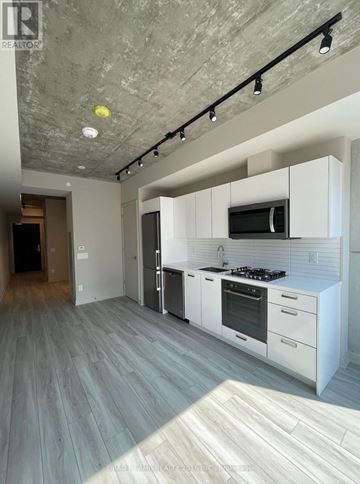 Toronto (Waterfront Communities) condo for rent - A modern kitchen with white cabinets and a grey floor.