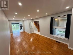 Markham (Milliken Mills West) apartment for rent - A spacious room with wooden flooring and a window with black curtains.