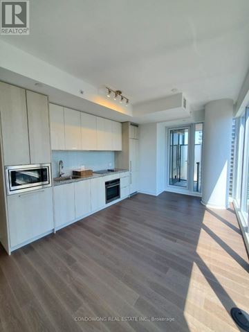 Toronto (Waterfront Communities) condo for rent - A modern kitchen with white cabinets and a wooden floor.