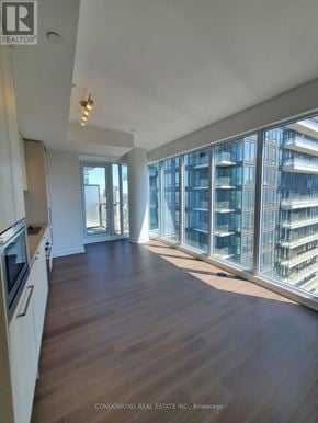 Toronto (Waterfront Communities) condo for rent - A spacious kitchen with wooden floors and a large window overlooking a cityscape.