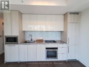 Toronto (Waterfront Communities) condo for rent - A modern kitchen with white cabinets and appliances.