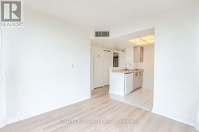 Toronto (Banbury-Don Mills) townhouse for rent - A white kitchen with a sink and cabinets is seen in a room with white walls and wooden flooring.
