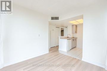 Toronto (Banbury-Don Mills) townhouse for rent - A white kitchen with a sink and cabinets is seen in a room with white walls and wooden flooring.