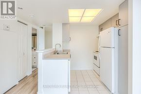 Toronto (Banbury-Don Mills) townhouse for rent - A white kitchen with a refrigerator, sink, and cabinets.