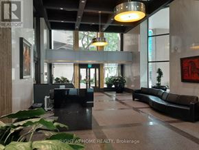 Toronto (Waterfront Communities) condo for rent - A modern office lobby with a black reception desk and a large painting on the wall.