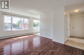 Whitby (Downtown Whitby) multi-family for rent - A room with wooden flooring and white walls, with a window showing a view of a street with cars and buildings.