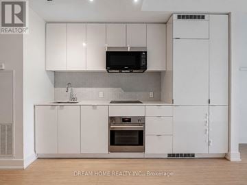 Toronto (Bay Street Corridor) condo for rent - A modern kitchen with white cabinets and a stainless steel oven.