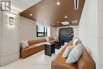 King (King City) condo for rent - A modern living room with a brown leather couch and a wooden ceiling.