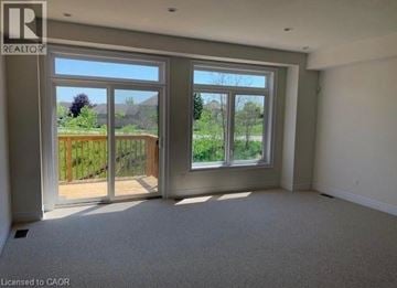Brantford townhouse for rent - A room with a large window and a sliding glass door leading to a backyard.