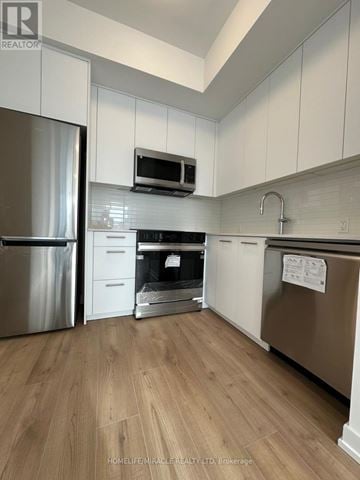 Kitchener condo for rent - A kitchen with white cabinets and a wooden floor.