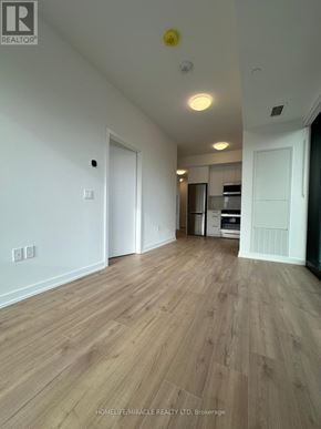 Kitchener condo for rent - A spacious room with wooden flooring and white walls.