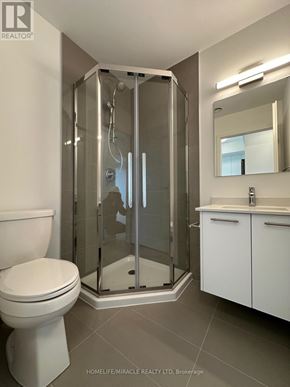 Kitchener condo for rent - A white toilet sits next to a walk-in shower in a bathroom.