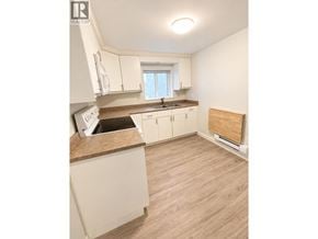 Burnaby apartment for rent - A kitchen with white cabinets and a wooden floor.