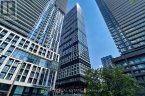 Toronto (Moss Park) condo for rent - A tall building with a glass facade stands in front of other buildings.