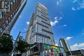 Toronto (Moss Park) condo for rent - A tall building with many windows stands in the middle of a city street.