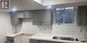 Brampton (Madoc) apartment for rent - A kitchen with grey cabinets and white tiles.