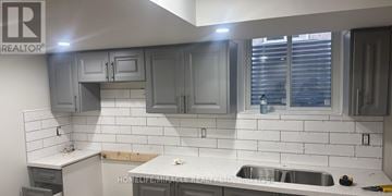Brampton (Madoc) apartment for rent - A kitchen with grey cabinets and white tiles.