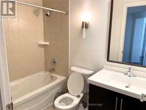 Toronto (Willowdale East) condo for rent - A white toilet sits next to a bathtub in a bathroom.