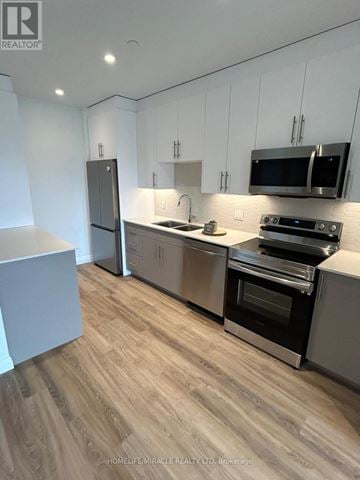 Kitchener condo for rent - A modern kitchen with wooden flooring and stainless steel appliances.