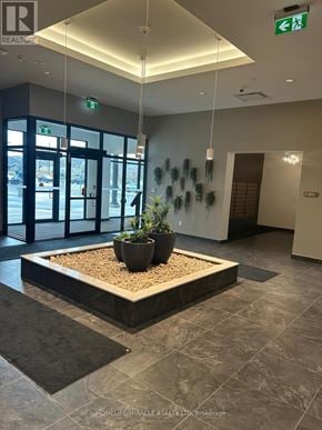 Kitchener condo for rent - A reception area with a planter in the middle and a green exit sign above.