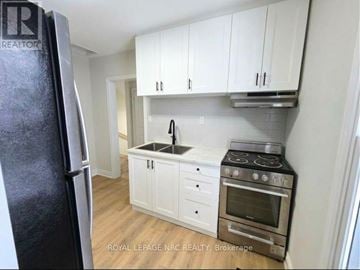 Port Colborne (East Village) fourplex for rent - A kitchen with white cabinets and a black fridge.