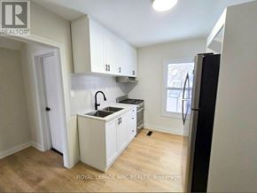 Port Colborne (East Village) fourplex for rent - A kitchen with white cabinets and a black refrigerator.