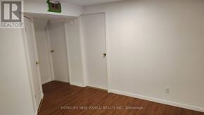Mississauga (Central Erin Mills) apartment for rent - A room with white walls and wooden flooring, with a door on the left and a small green object on the ceiling.