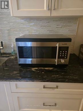 Toronto (Lawrence Park North) apartment for rent - A silver microwave oven sitting on a black granite countertop.