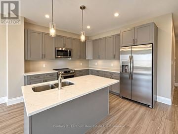 Prince Edward County (Picton Ward) townhouse for rent - A modern kitchen with a stainless steel refrigerator and a white countertop.