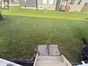 Ottawa townhouse for rent - A well-maintained lawn in front of a house with a brick pathway leading to a small garden area.