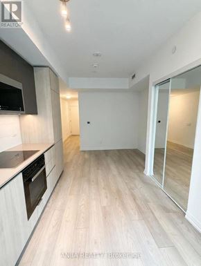 Toronto (Waterfront Communities) condo for rent - A modern kitchen with wooden flooring and a glass door leading to another room.