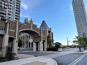 Mississauga (City Centre) condo for rent - A street view of a building with a large archway entrance and a sign that reads "Canada Home Group Realty Inc. Brokerage.".