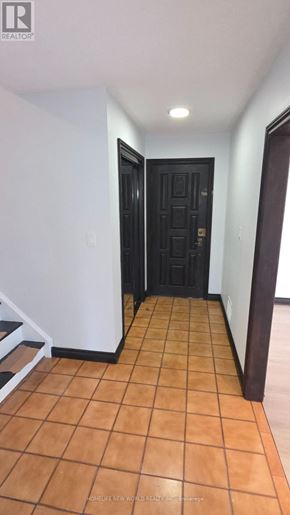 Toronto (Mount Olive-Silverstone-Jamestown) apartment for rent - A hallway with a black door and brown tiled flooring.