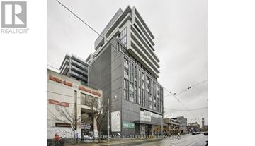 Toronto (Kensington-Chinatown) condo for rent - A tall building with a grey facade stands in the middle of a street.