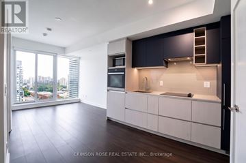 Toronto (Church-Yonge Corridor) condo for rent - A modern kitchen with dark blue cabinets and a view of the city.