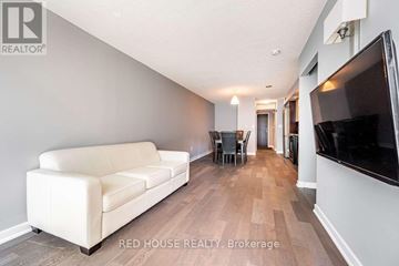Toronto (Waterfront Communities) condo for rent - A living room with a white couch and a television on the wall.
