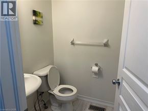 Kitchener townhouse for rent - A white toilet sits in a small bathroom with a white door.
