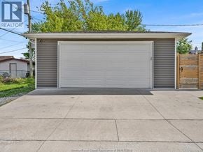 Tecumseh apartment for rent - A two-car garage with a grey roof and a wooden fence in front.