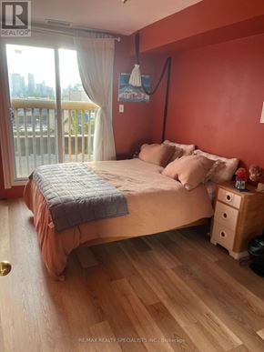 Toronto (Palmerston-Little Italy) multi-family for rent - A bedroom with a bed, nightstand, and a balcony with a view of the city.