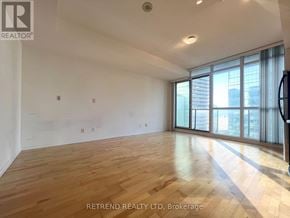 Toronto (Waterfront Communities) condo for rent - A spacious room with wooden flooring and large windows.