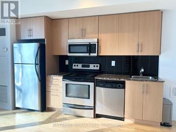 Toronto (Waterfront Communities) condo for rent - A kitchen with wooden cabinets and stainless steel appliances.