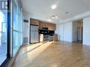 Toronto (Waterfront Communities) condo for rent - A kitchen with wooden floors and a black fridge.