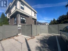 Toronto (East York) triplex for rent - A house with a grey fence and a car parked in front.
