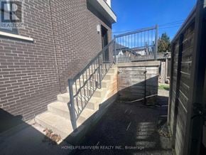 Toronto (East York) triplex for rent - A staircase with a metal railing leads to a building entrance.