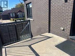 Toronto (East York) triplex for rent - A brick wall with a black gate in front of a house.