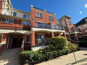 Oakville (Ro River Oaks) townhouse for rent - A red brick building with a balcony and a bicycle parked in front.