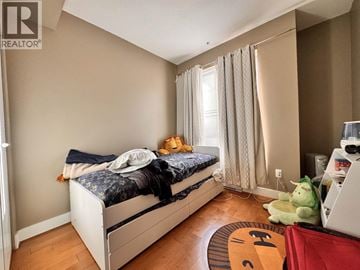 Burnaby townhouse for rent - A bedroom with a bed, a window with curtains, and a rug with a cat face on it.