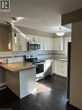 Kitchener apartment for rent - A kitchen with a stove, oven, microwave, and cabinets.