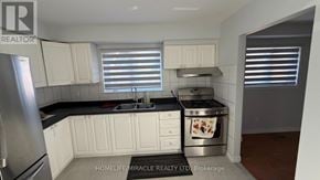 Toronto (Malvern) apartment for rent - A kitchen with white cabinets and a black countertop.