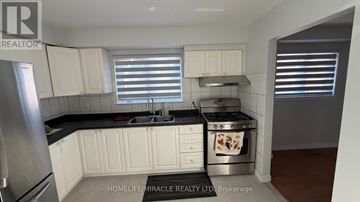 Toronto (Malvern) apartment for rent - A kitchen with white cabinets and a black countertop.